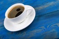 Overhead view of a freshly brewed mug of espresso coffee on blue rustic wooden background with woodgrain texture. Coffee break Royalty Free Stock Photo