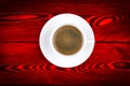 Overhead view of a freshly brewed mug of espresso coffee on red rustic wooden background with woodgrain texture. Coffee break Royalty Free Stock Photo