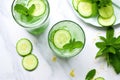 overhead view of a glass of cucumber and mint infused water on stack of magazines