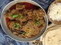 Overhead view of Goat curry, Mutton curry, Nihari, Rogan Josh in a bowl with Chapati and plain Rice