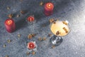 Overhead view of grapefruit martini cocktail with dried roses flowers and petals, surrounded candles on dark gray table surface