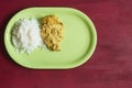 An overhead view of a green dish with a pile of cooked basmati rice on red wood background with copy space