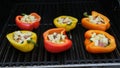 Overhead view of grilling stuffed savory bell peppers topped with melted cheese over the fire on an outdoor summer BBQ Royalty Free Stock Photo