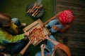 Overhead view on group of friends eating pizza nearby burning campfire