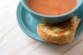 Overhead view of half a grilled cheese sandwich and tomato soup. Served on a wood table. Copy space. Royalty Free Stock Photo