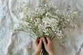 Overhead view of hands holding a bunch of white gypsophila flowers