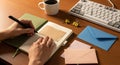 Hands writing in a notebook with coffee and keyboard on wooden desk Royalty Free Stock Photo