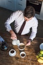 Overhead view of handsome man pouring milk into bowl with muesli while having breakfast at home. Royalty Free Stock Photo