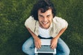 Overhead view of happy student sitting on the ground, working on laptop. Smiling man with curly hair using laptop for chatting Royalty Free Stock Photo