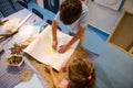 Overhead view of kids holding pencils and drawing on white paper sheet in creative art workshop. Creativity and fine art