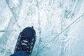 An overhead view of the legs in black skate boots against the background of the ice rink.