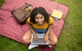 Overhead view of lovely black girl with laptop computer studying online on picnic blanket at park Royalty Free Stock Photo