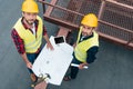 overhead view of male engineers in safety vests and helmets working with blueprints digital tablet and tools