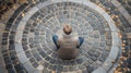 Overhead view of a man sitting alone at the center of a circular stone spiral pattern Royalty Free Stock Photo