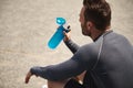 Overhead view of a middle aged sportsman, mature athlete resting and drinking water, rehydrating his body after sport training.