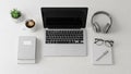 Overhead view of a modern desk setup with laptop, headphones, coffee, books, plant, and glasses Royalty Free Stock Photo