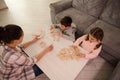 Overhead view of a mom and kids playing board games, building wooden structures, constructions on the table in home living room. Royalty Free Stock Photo