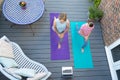 Overhead View Of Mother And Daughter Following Online Exercise Class On Laptop At Home On Deck