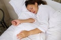 View from above beautiful young woman sleeping, lying in bed and keeping eyes closed while covered with white blanket. Royalty Free Stock Photo