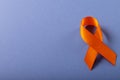 Overhead view of orange leukemia awareness ribbon isolated against blue background, copy space