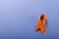 Overhead view of orange leukemia awareness ribbon isolated over blue background, copy space