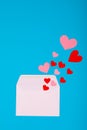 Overhead view of pink and red hearts coming from white envelope on blue background with copy space Royalty Free Stock Photo