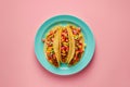 Overhead view of a plate of fresh mexican tacos on a bright color background