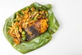 Overhead view of popular grilled stingray fish with spices and vegetable served on banana leaf