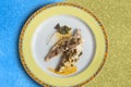 Overhead view of a presentation on a decorated plate of cooked baked sea bream with sauce.