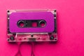 Overhead view of purple cassette tape on pink background