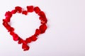 Overhead view of red rose petals arranged as heart shape with copy space on white background Royalty Free Stock Photo