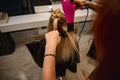 Close-up. Overhead view of redhead female hairdresser combing and drying client hair in beauty parlor, performing stylish hair Royalty Free Stock Photo