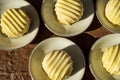 Overhead view of rows of small round lemon cakes covered with striped frosting