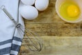 Ready to bake with eggs and a wisk on a wooden background. Royalty Free Stock Photo