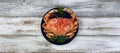 Overhead view of a single cooked large Dungeness crab on dark blue plate with white wooden table underneath