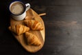 Overhead view of small croissants on wood with cup of coffee and spoon,