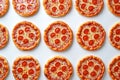 Overhead view of small pepperoni pizzas forming a repeating pattern, creating a visually appealing food background Royalty Free Stock Photo