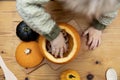 Overhead view of a toddlers hands playing with a pumpkin whilst making a lantern decoration for halloween