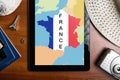 Overhead view of traveler`s accessories and map of France on tablet, travel concept background, map of France on tablet display an