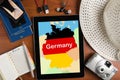 Overhead view of traveler`s accessories and map of Germany on tablet, travel concept background, map of Germany on tablet display