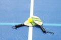 Overhead view of two pickleball paddles on a whiffle ball on a court