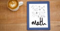 Overhead view of various math equations in digital tablet by coffee cup at table