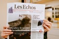 Overhead view of woman reading Les Echos French newspaper breaki