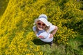 Overhead view of a woman in a yellow wildflower field wearing hiking clothing and a straw sun hat. Concept for seasonal allergies