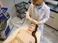 Top view of a woman getting facial laser treatment for hair removal, skin smoothing and age and pigments spots treatment on her