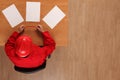 Overhead view of worker in red uniform and hardhat reading papers Royalty Free Stock Photo