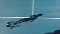 Overhead view of young african american female tennis player with shadow playing on blue court