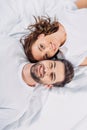 overhead view of young smiling couple in love looking at camera while lying Royalty Free Stock Photo