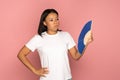 Overheated african woman using paper fan suffer from heat sweating, cools herself, feels sluggish