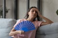 Overheated displeased millennial arabic indian woman using paper fan.